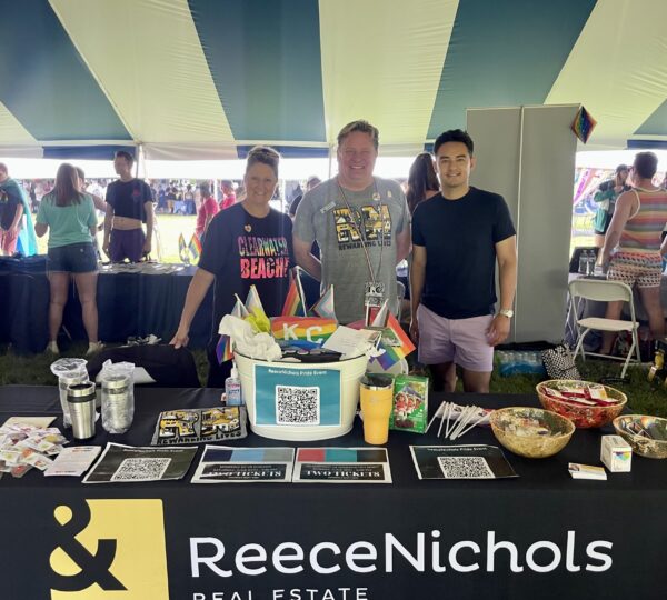 three people standing behind table at a festival
