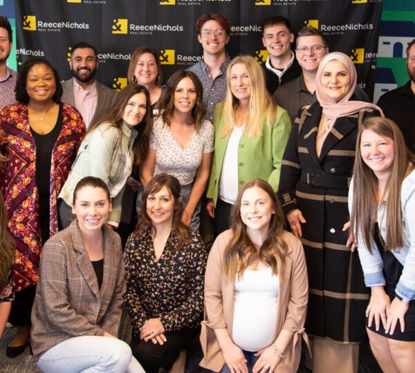 group of real estate agents standing in front of banner